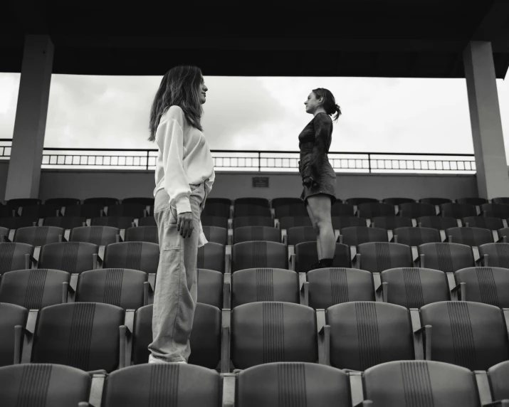 two girls standing in an empty stadium, both facing one another