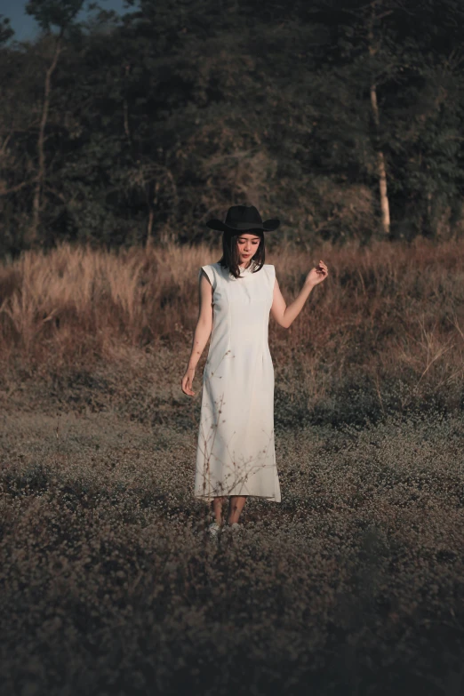 a woman in white dress and black hat posing