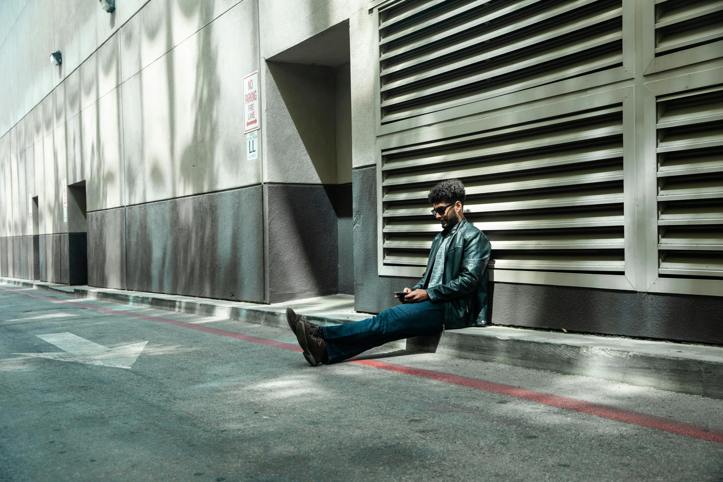 a man sitting on the side of a building talking on his phone