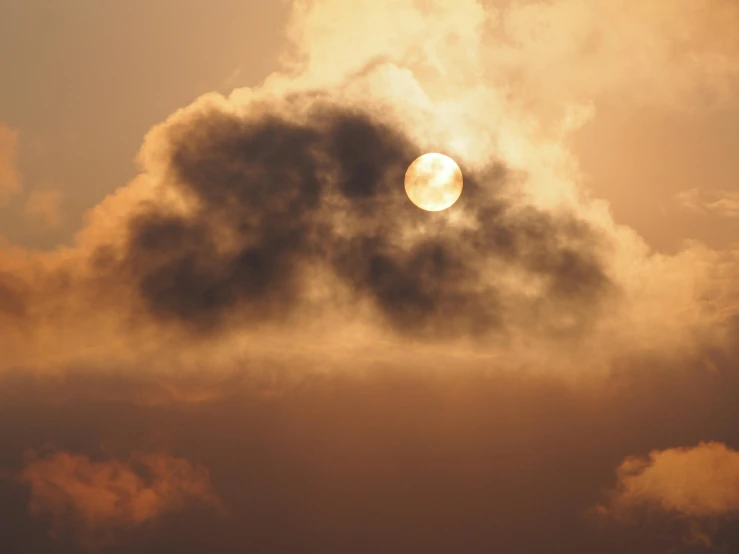 the sun is setting behind a dark cloud in a cloudy sky