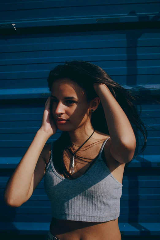 a woman with her hair up stands against a building