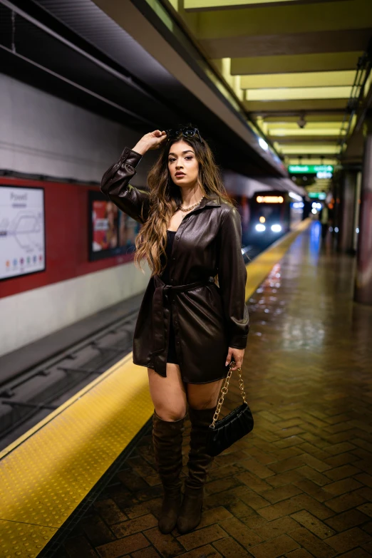 the woman wearing a brown leather dress stands on a platform