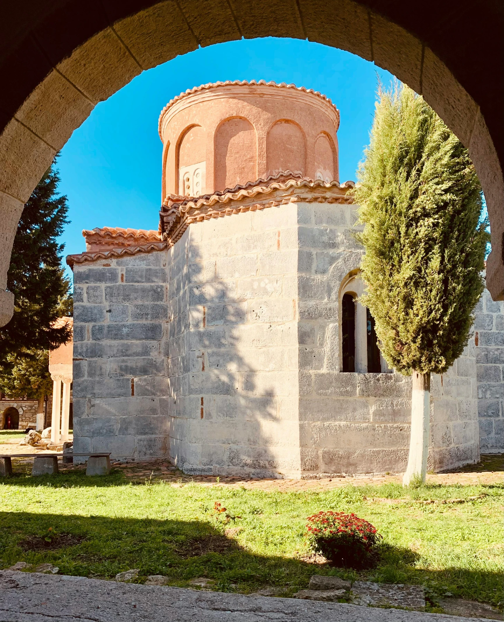 a round stone building is seen through an arch