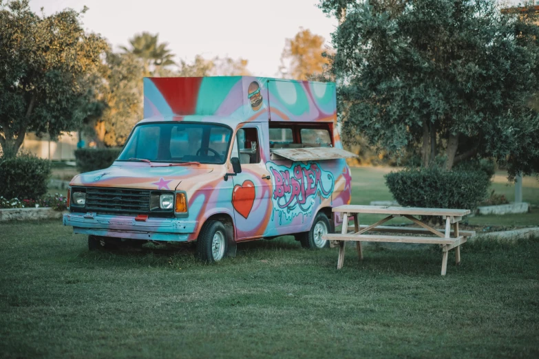 an ice cream truck painted with graffiti is parked on the grass