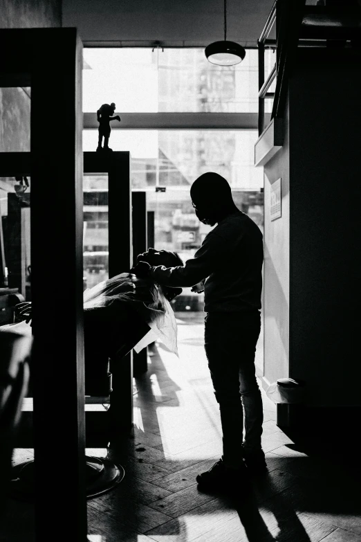 a young man stands next to his hairdresser while the sun shines down on him