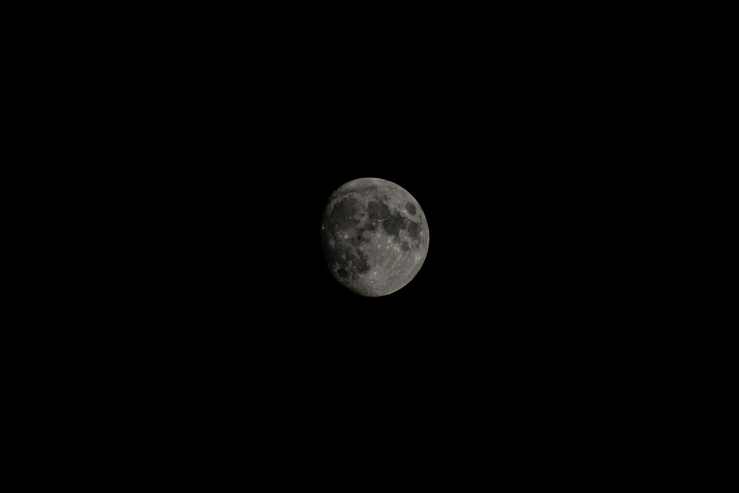 the moon appears black in the distance in the night sky