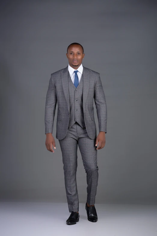 a black man dressed in a suit standing against a gray background