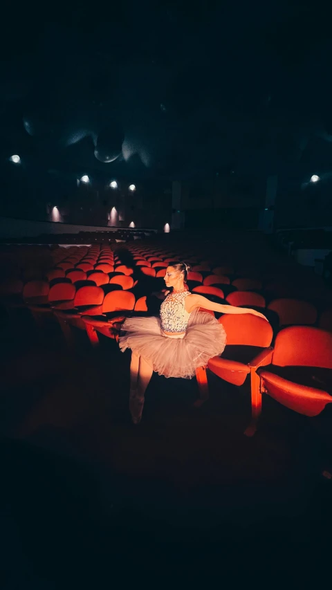 a young ballerina poses in an auditorium