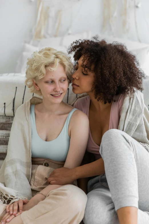 two women in pastel clothes sitting on the couch