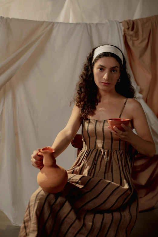 a woman holding a red tea cup, with one hand in a pottery pot