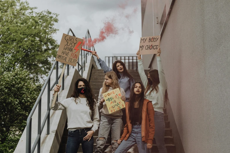 a group of girls holding protest signs standing up stairs