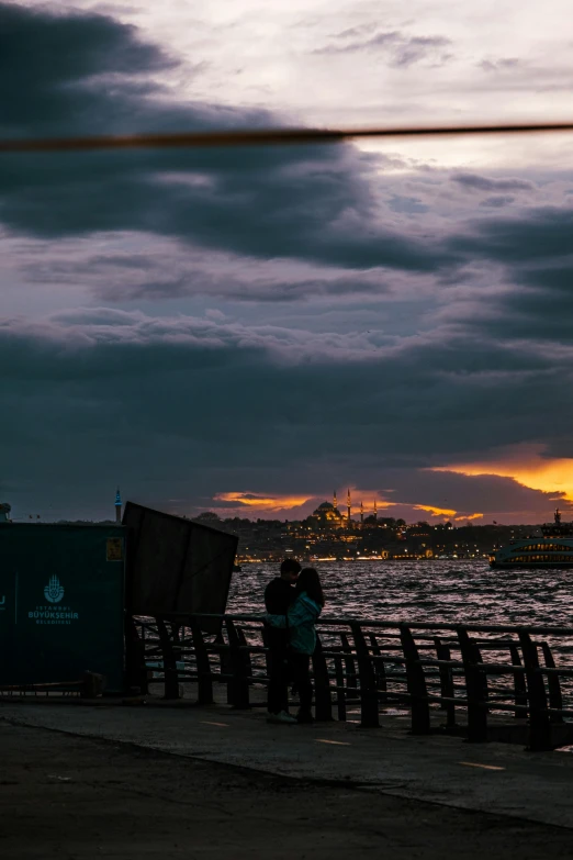 the person is standing at the water's edge as the sun goes down