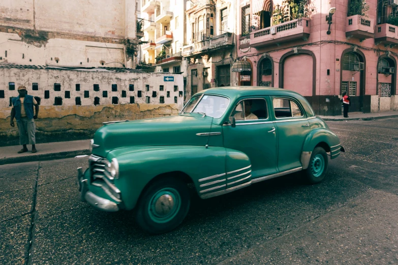 an old fashioned car sits in front of an older building