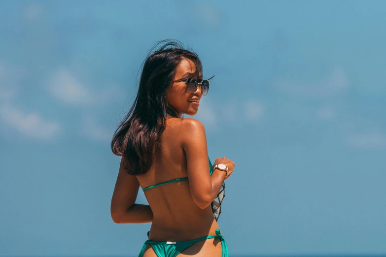 a woman on the beach in a green bikini