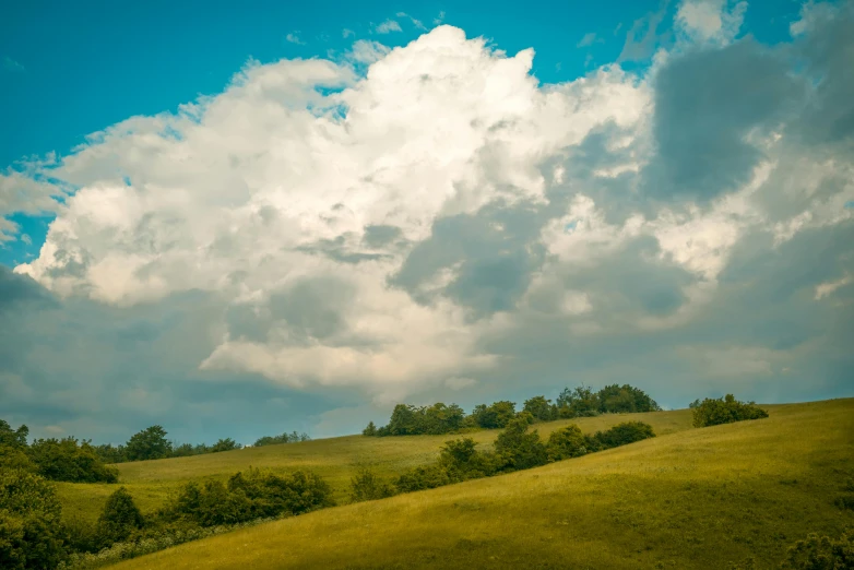 some green hills on a sunny day with clouds above them