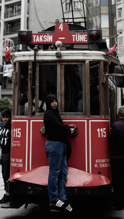 a man leaning against a red trolly in the middle of a street
