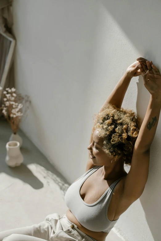 a woman sitting on a bed with her hands hanging over her head