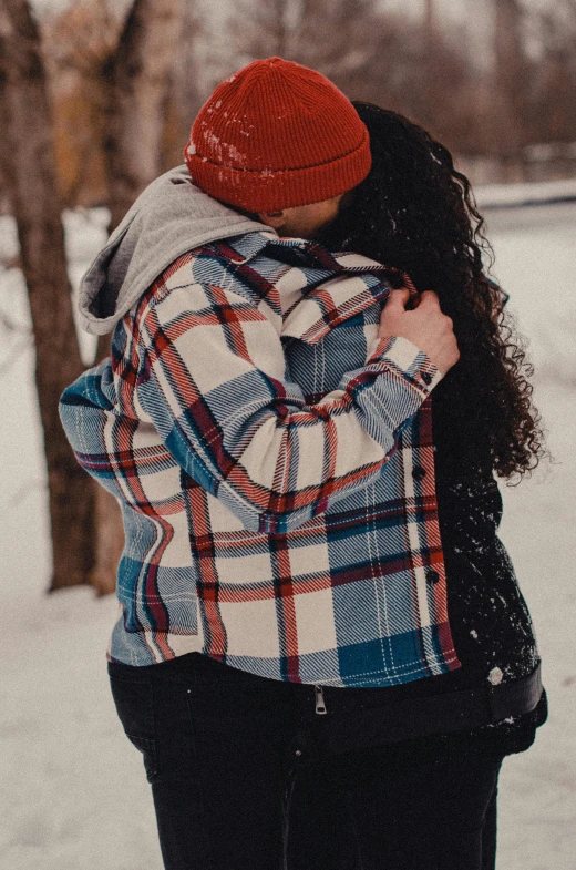 a couple is emcing in the snow in a forest