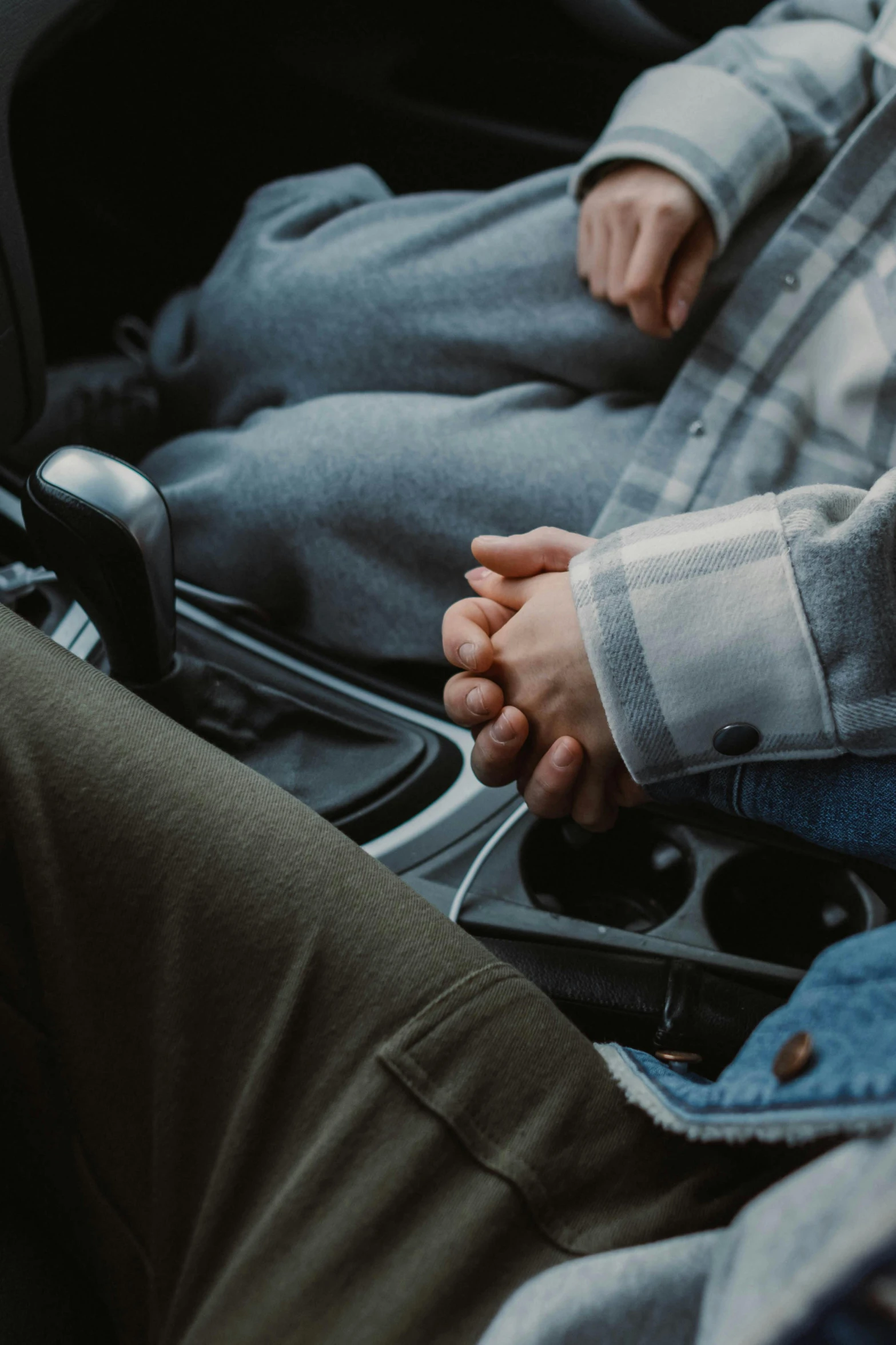 two persons with one hand on the steering wheel of a car