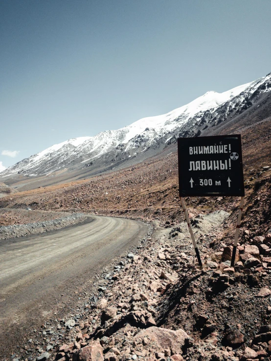 a road leading towards mountains with a sign stating not to cross