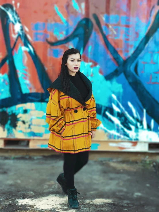 a woman with a black scarf standing in front of some graffiti