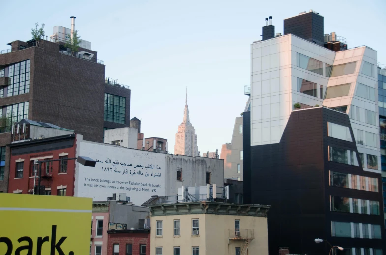 city buildings at the foot of tall buildings with an image of a spire on top of one