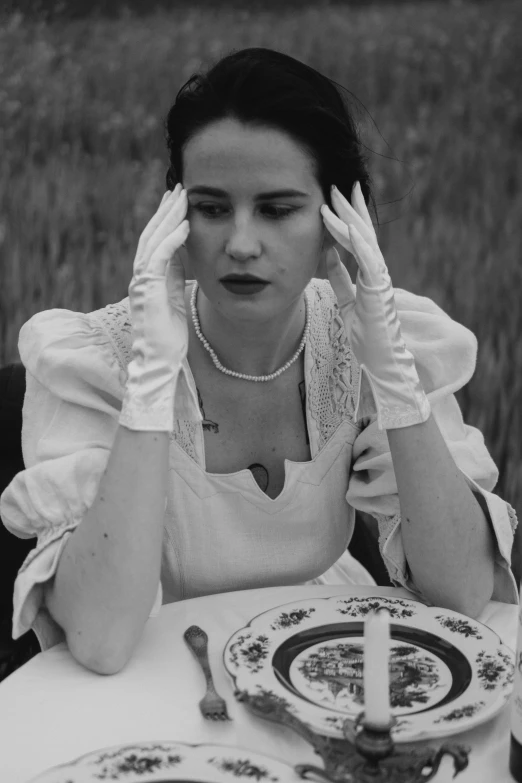 a woman holding her head while sitting at a table