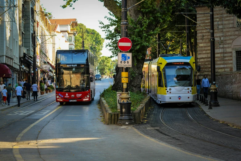 buses on a street with people walking about