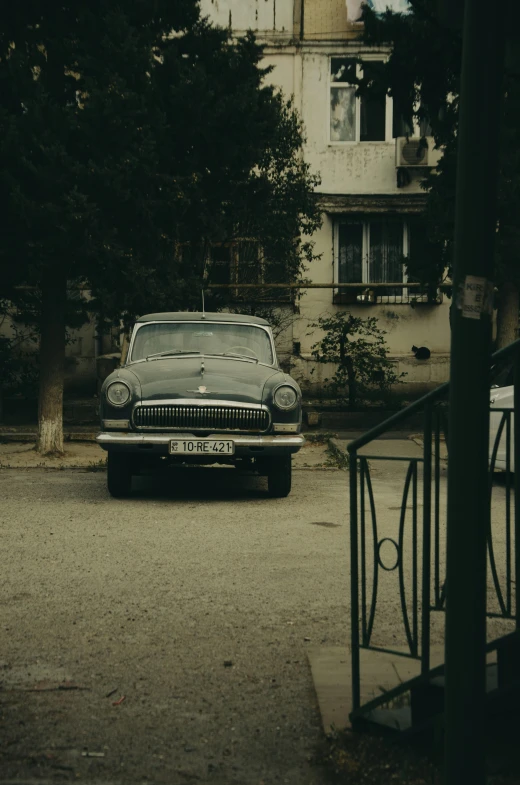 an old, green car parked on a driveway