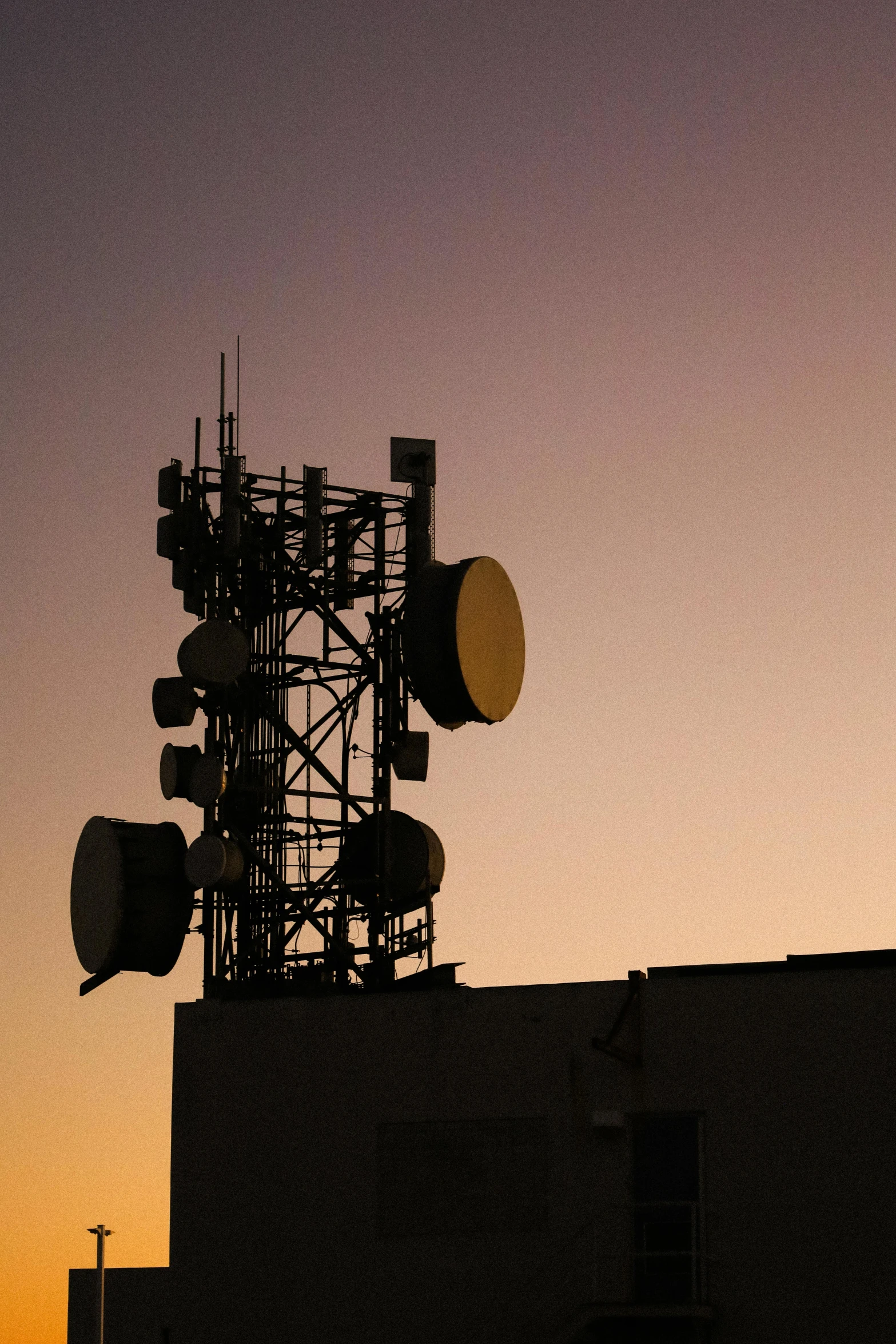 the silhouette of a radio tower against the sunset