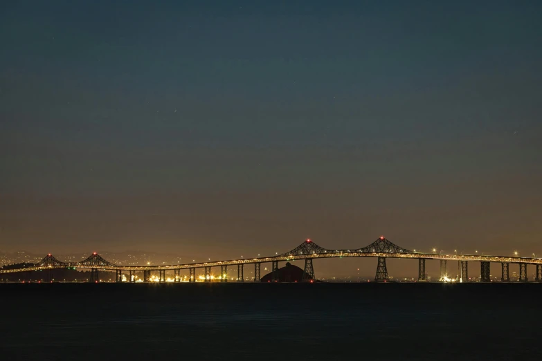 view of a long bridge over water at night