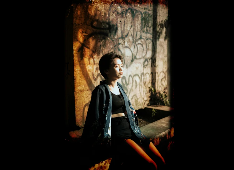 a boy sitting alone in front of a graffiti covered wall