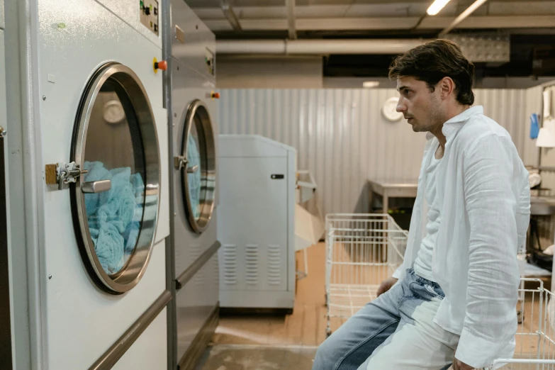 a man standing by a washing machine looking at the clothes