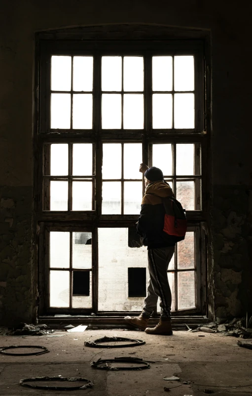 man looking out window, in dirty building