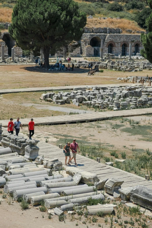 a group of people walking on a dirt covered area