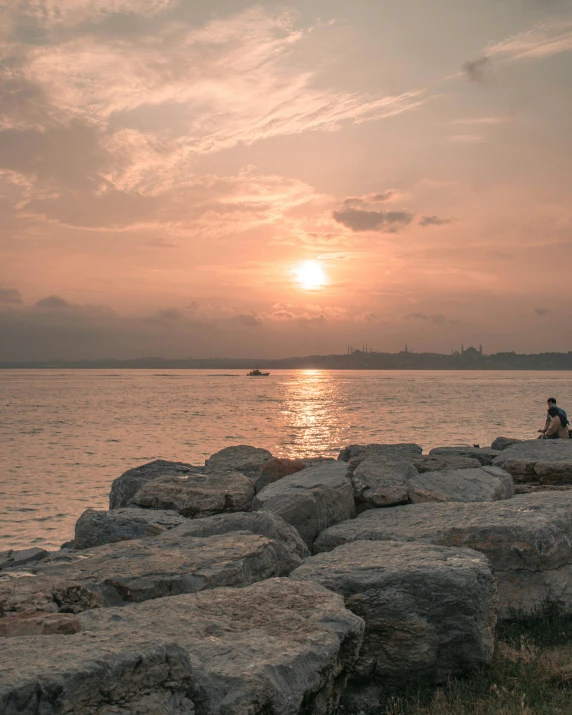 people are sitting on rocks next to the ocean