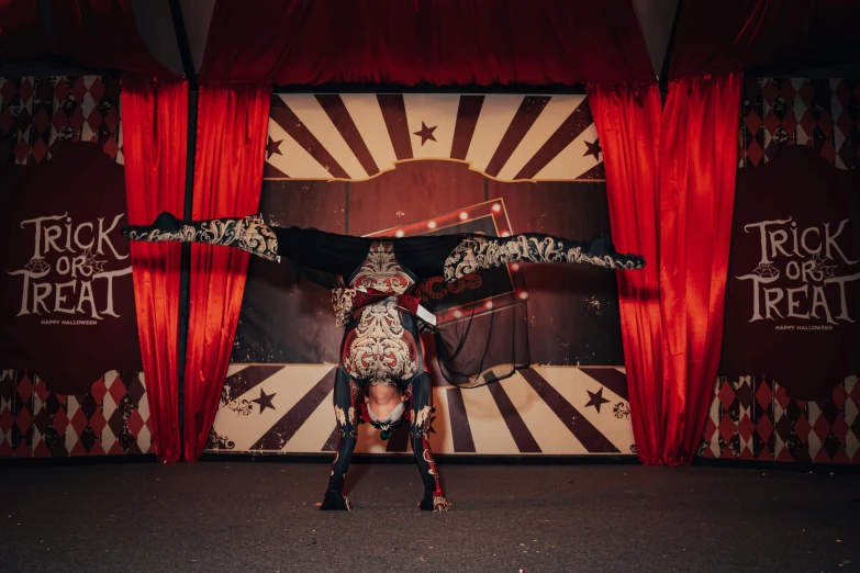 a performer on stage in front of red curtains