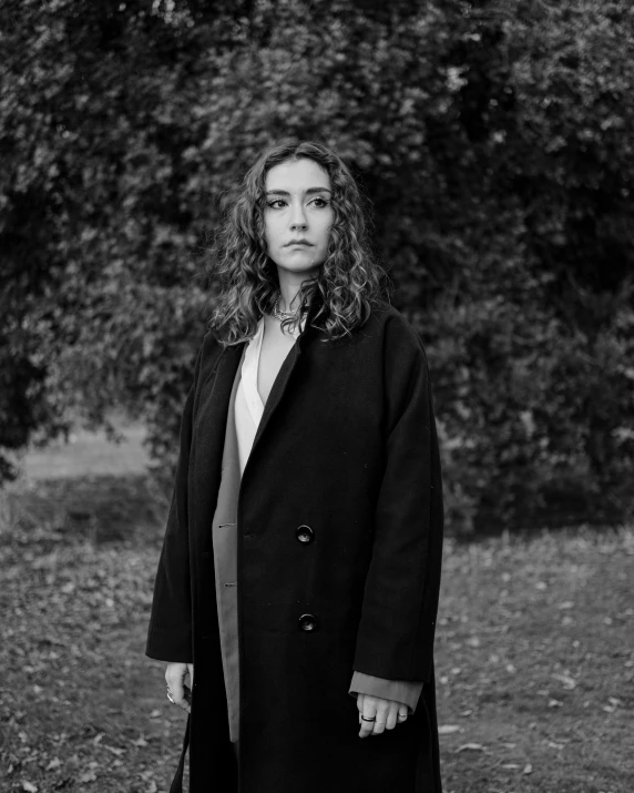 black and white pograph of woman with coat walking in field