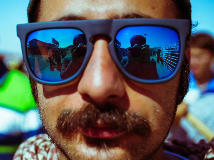 this is a man wearing sunglasses with reflection of two horses