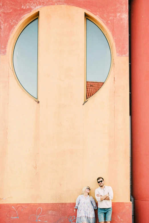 two people sitting on a wall and looking into a window