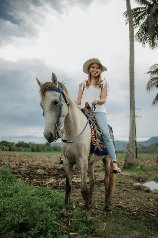 a girl riding a white horse in a field