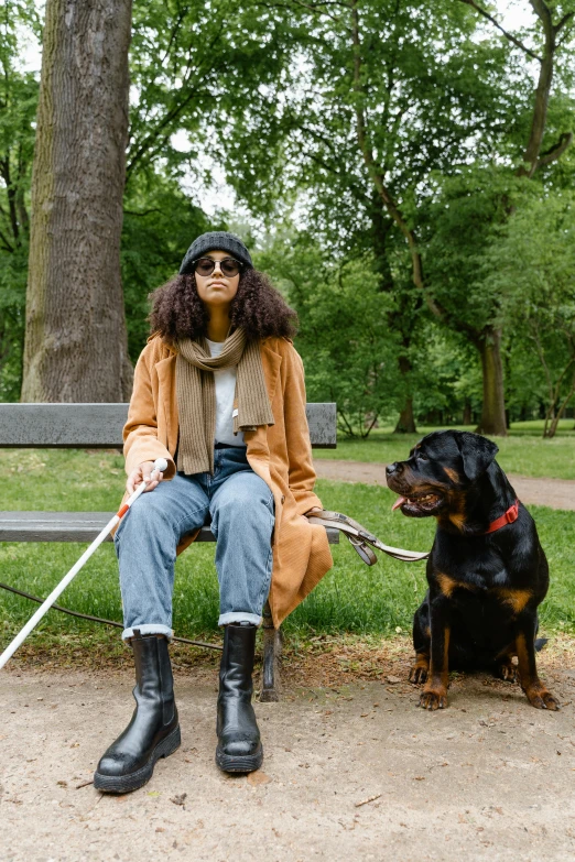 woman in long cardigan sitting next to a black dog