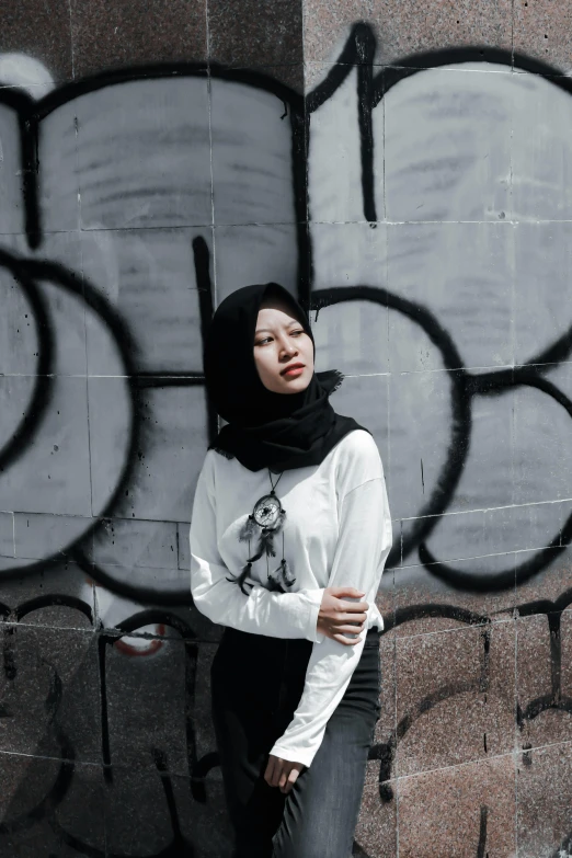 a woman is leaning against a wall wearing a scarf