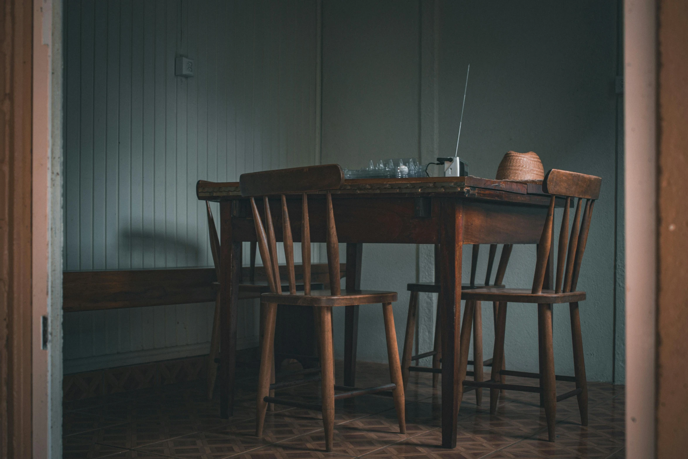 a table with a hat and two wooden chairs