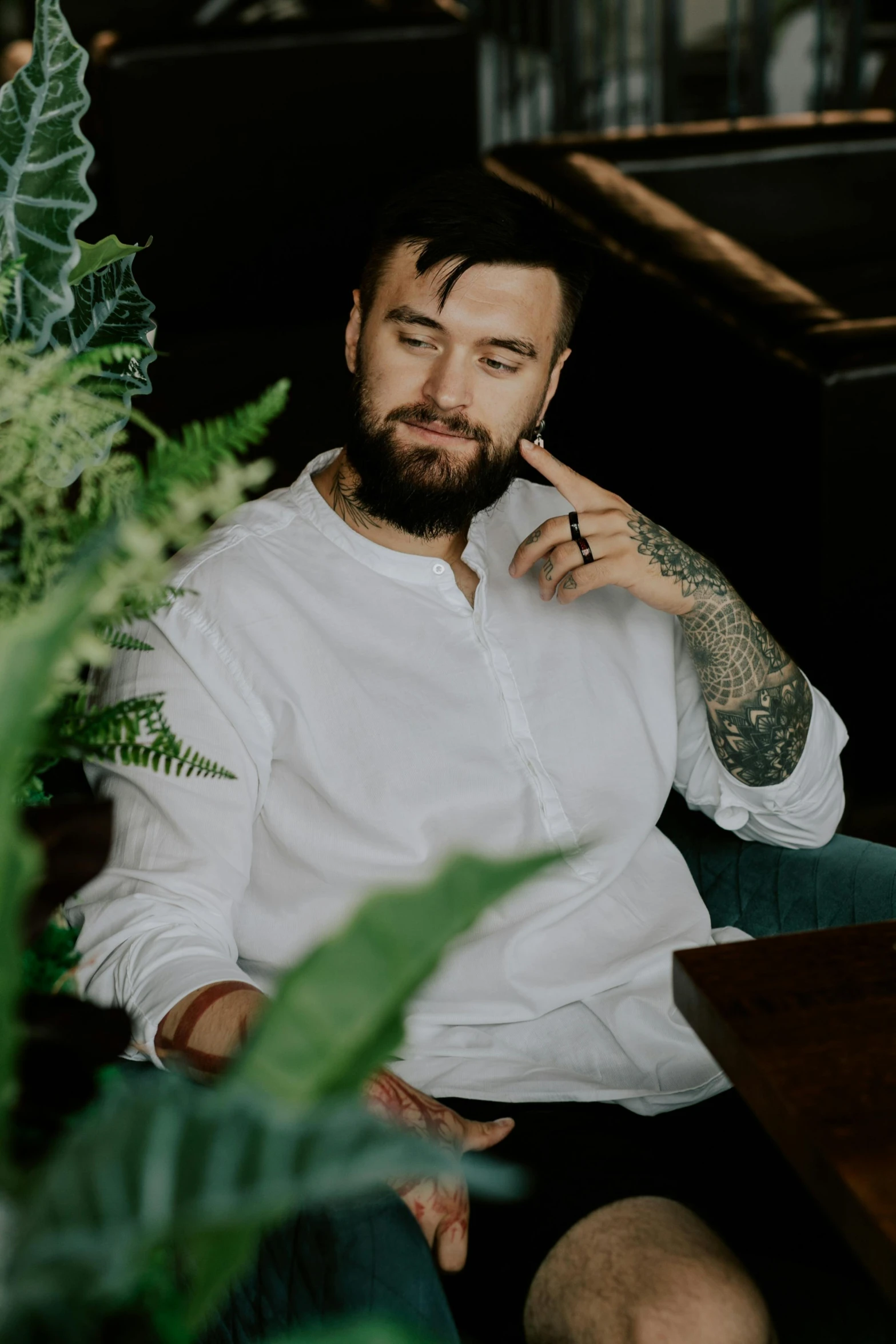 a man sitting on top of a couch next to a plant