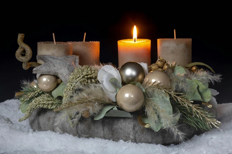 two candles are next to each other and decorated with green greenery