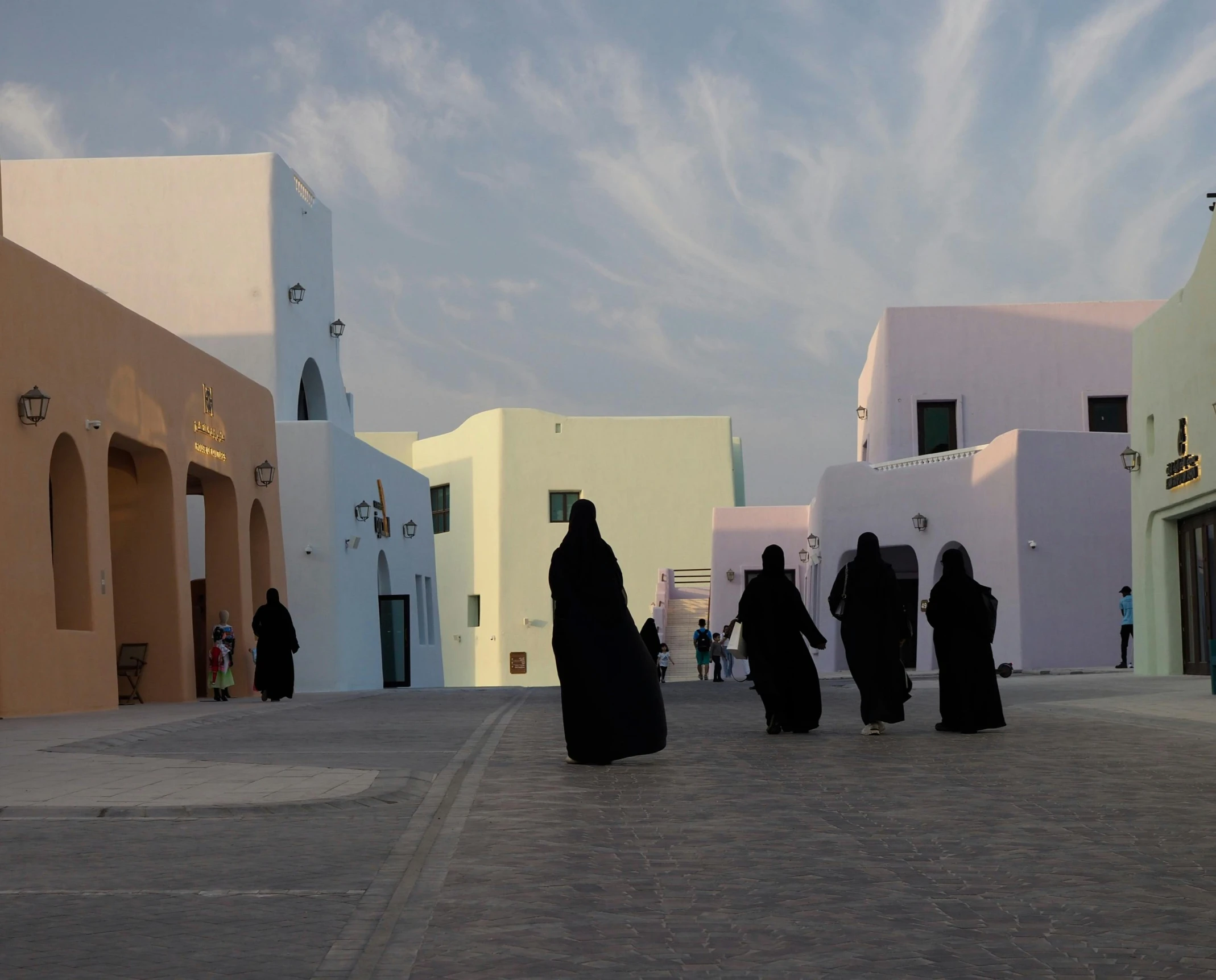 several women dressed in a period of dress walk through a city