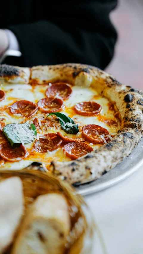 pizza with toppings is on the plate next to bread