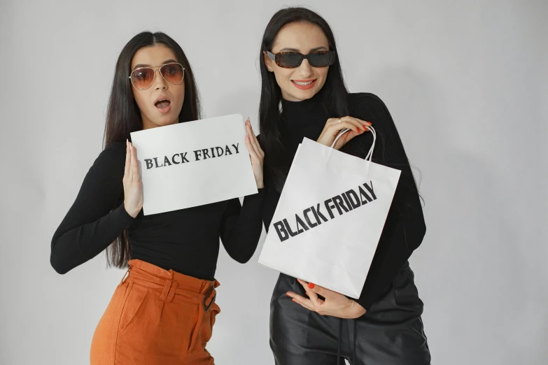 two woman holding up white signs reading black friday