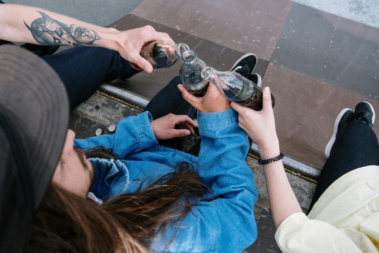 two people sit on the sidewalk holding cell phones